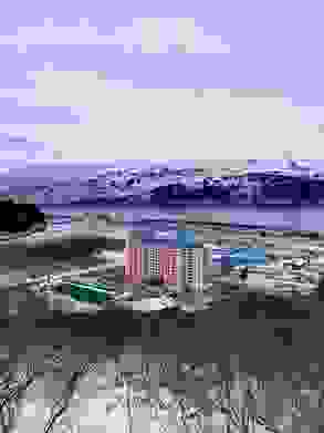 A pink, yellow, and blue apartment building next to a water channel and mountains in Alaska
