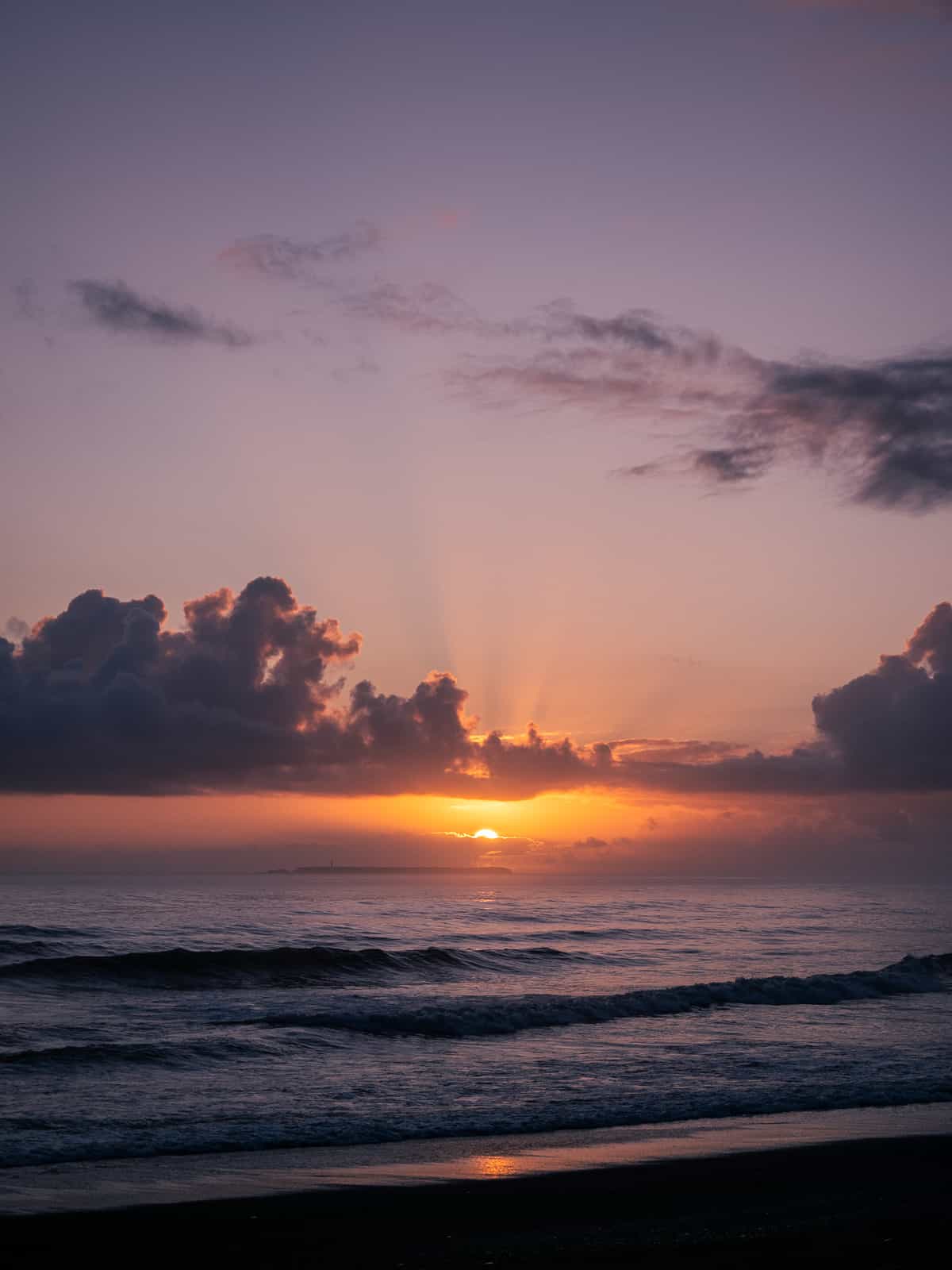 Sunset on the ocean, the sun is halfway hidden by the horizon