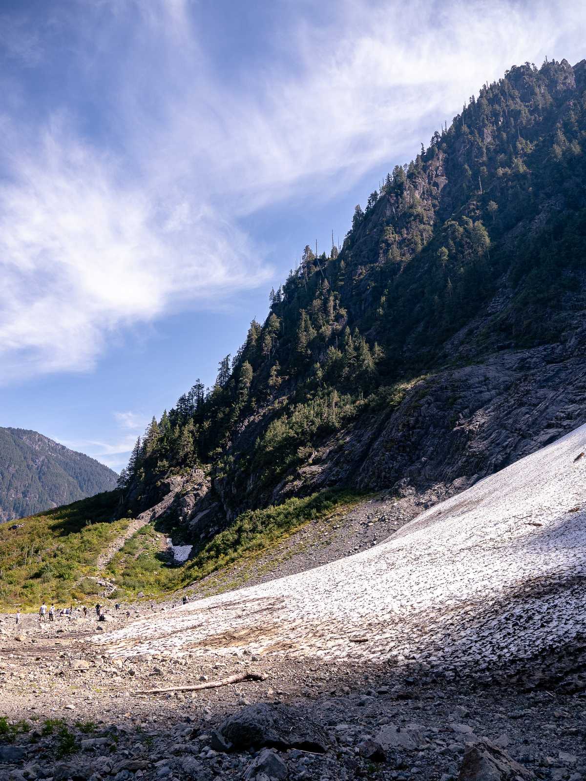 A mountain of snow leads up to a mountain ridge in the distance.