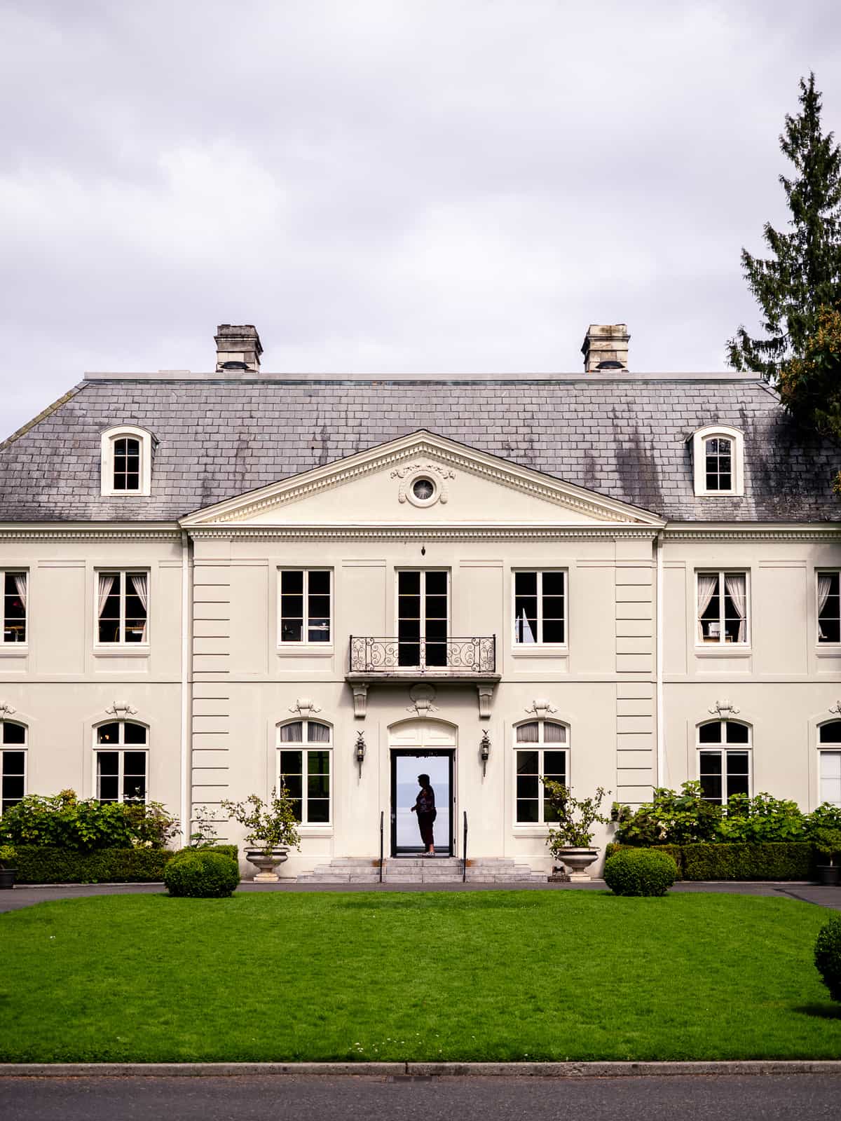 A colonial era house, with the front door open and a person visible inside