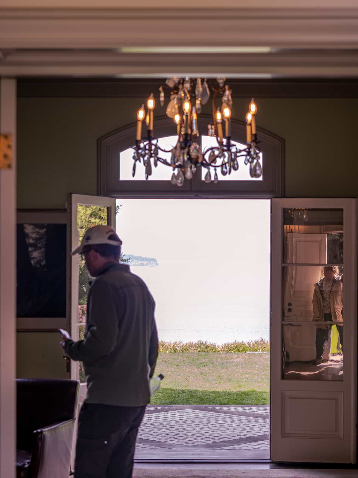 A person walks inside a front door, with a chandelier visible inside.