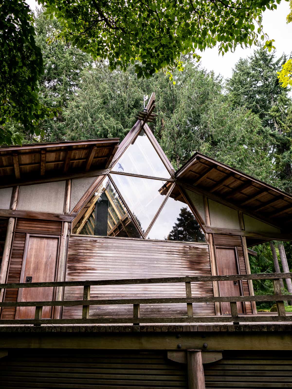 The sky reflects off of triangular shaped windows on a wood-paneled building