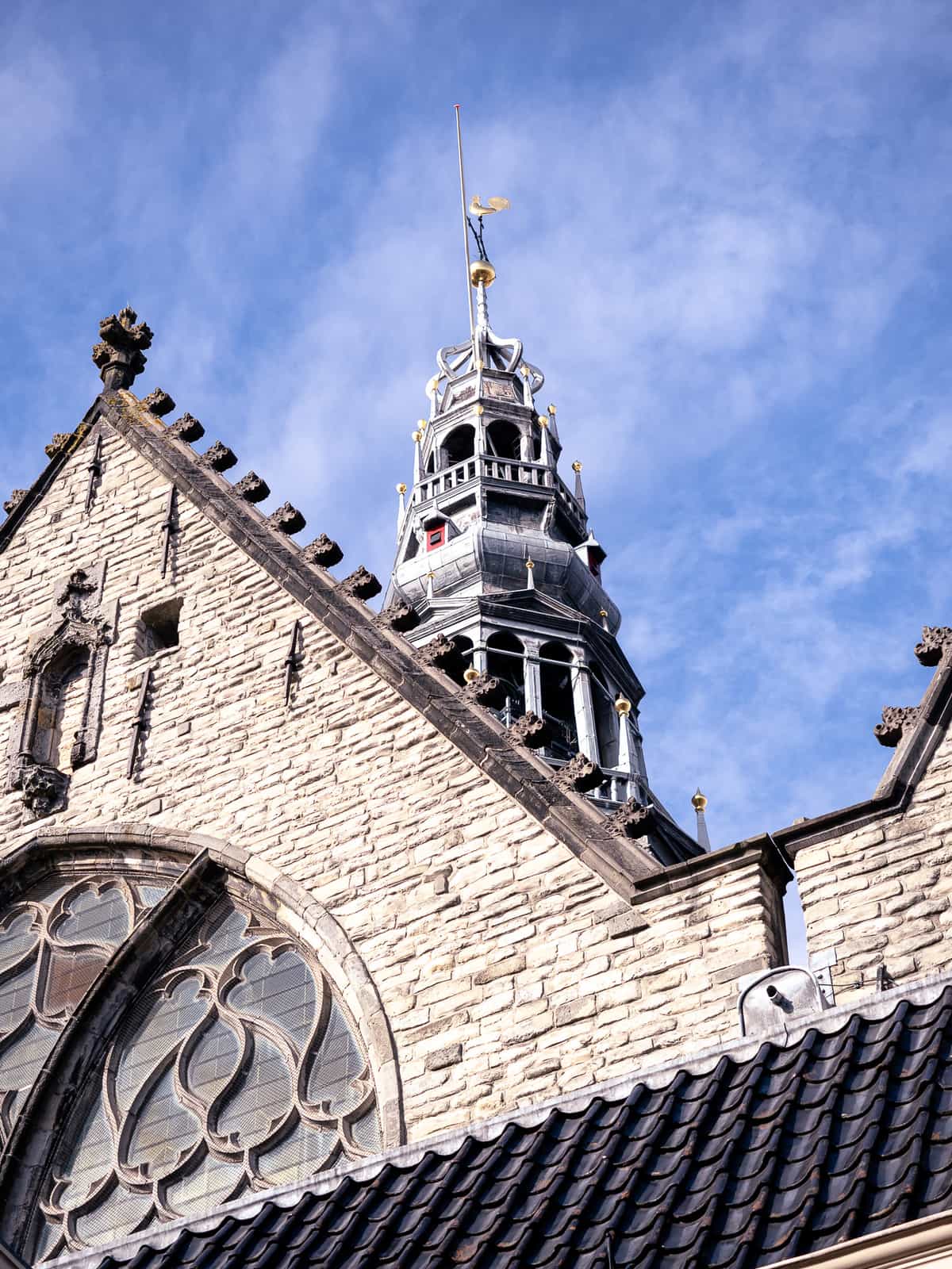 A zoomed in picture of a church tower, with a gold statue on top