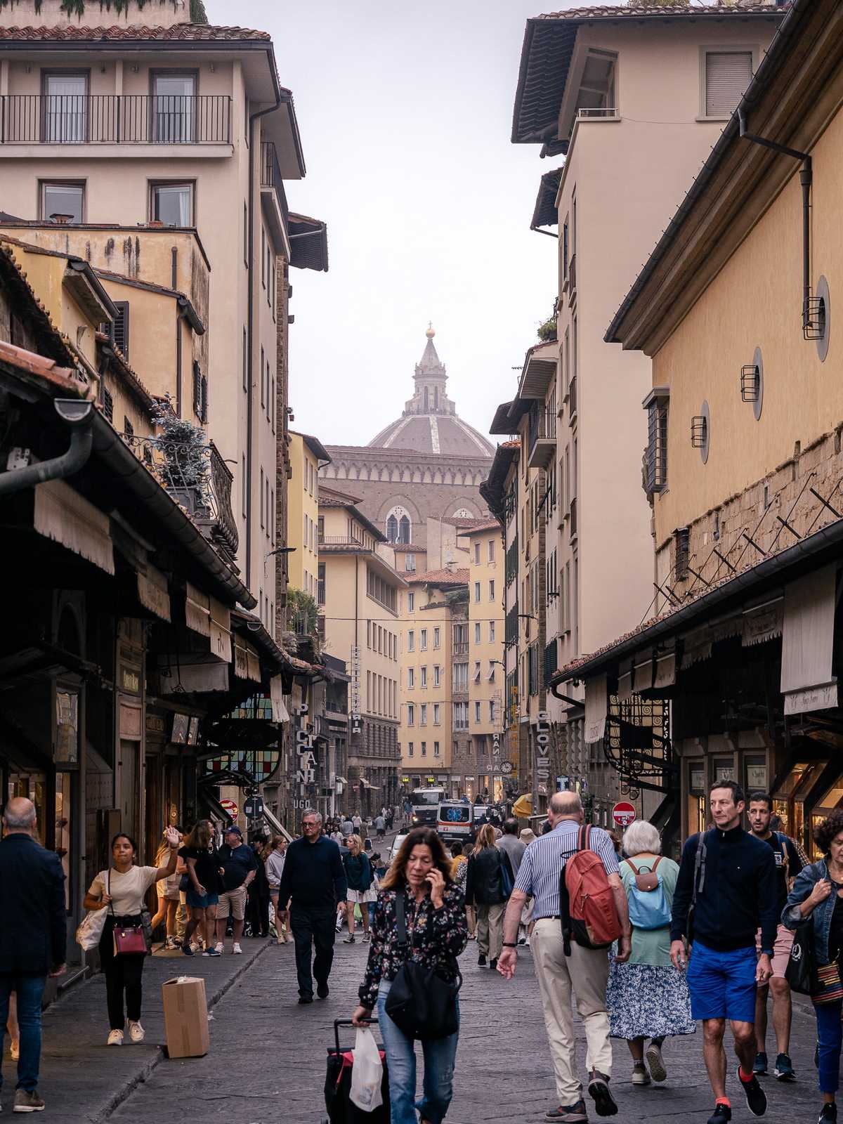 A hazy morning view of people walking on an old street in Florence, Italy