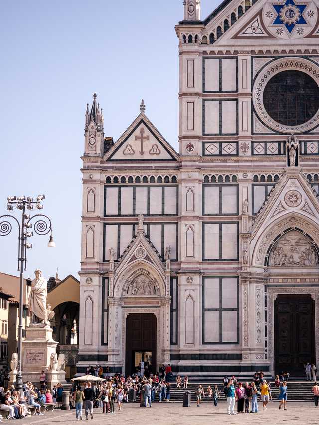 The large face of a church towers over tourists in Florence