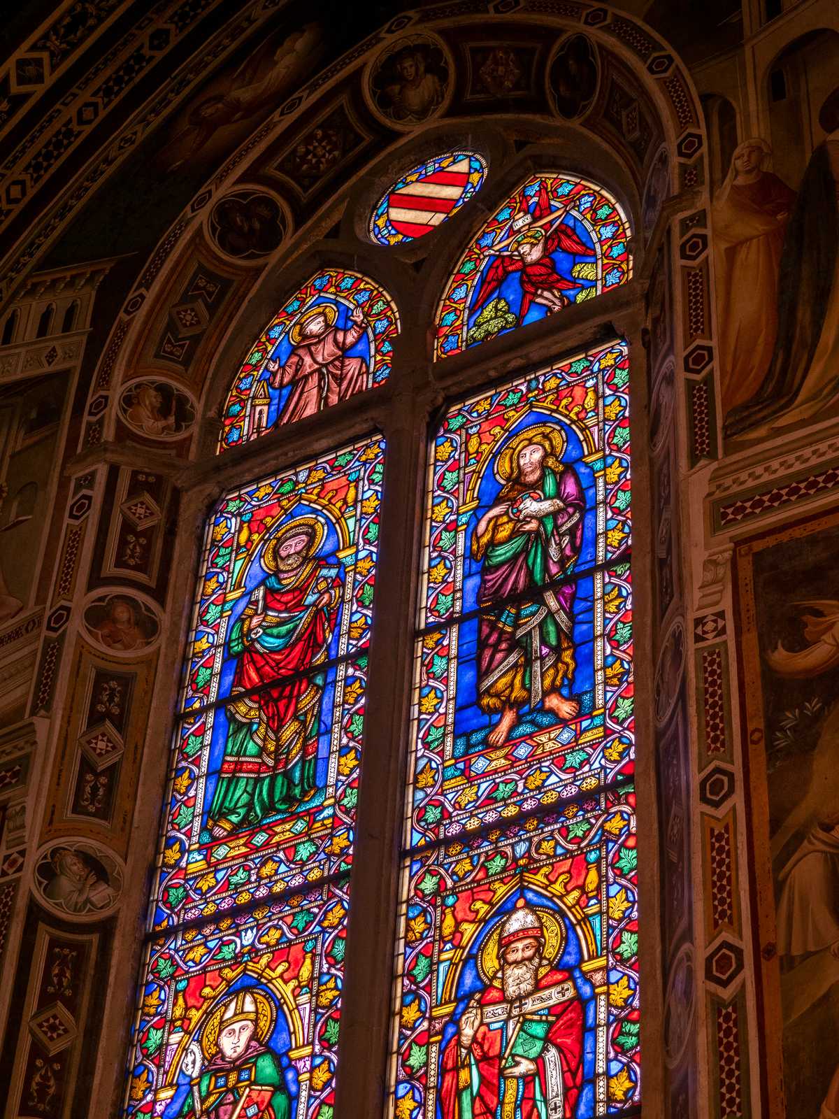 Stained glass windows glow colorfully, depicting saints and religious figures