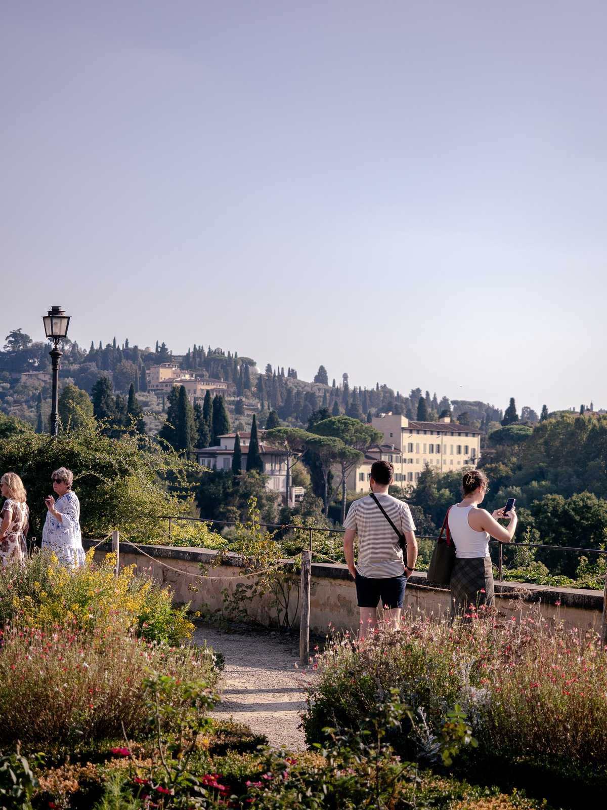 Tourists look out onto the Italian country-side from a gravel garden