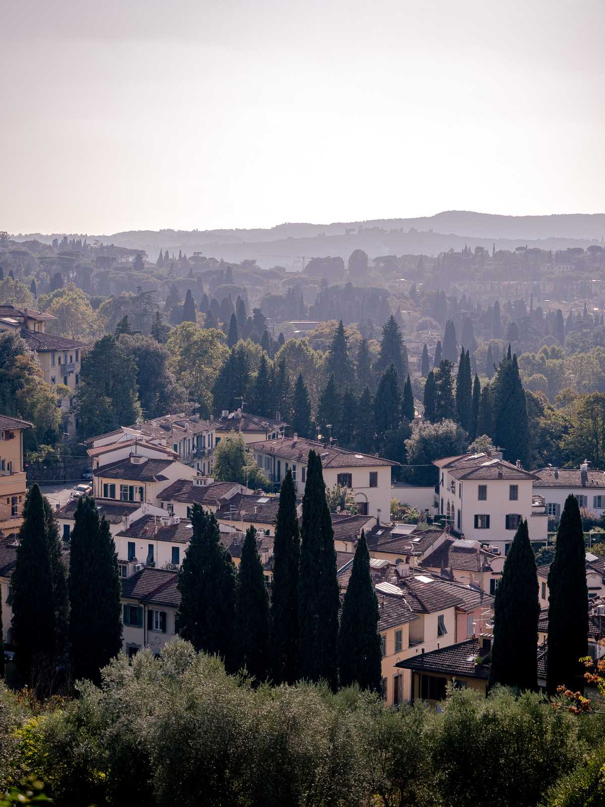 Apartment buildings fill the foreground with the Italian countryside extending out into the hazy distance