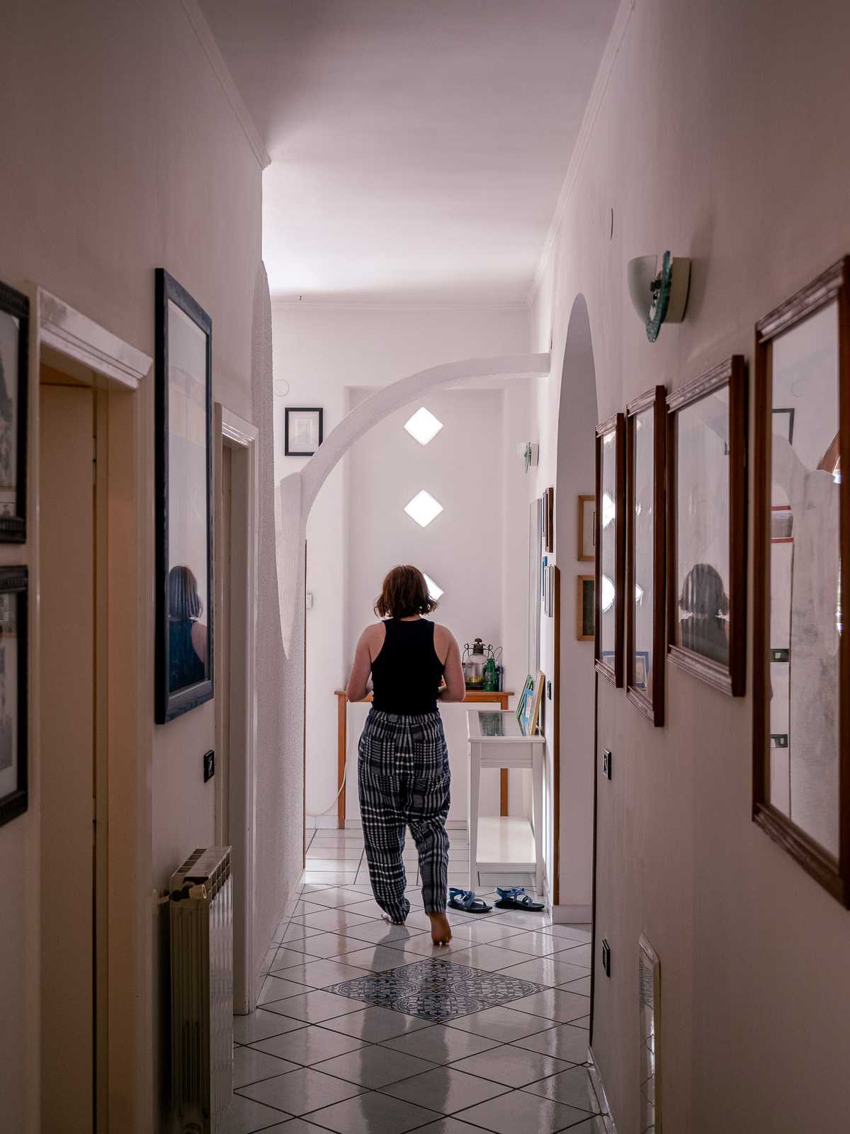 A person walks down a hallway, with diamond windows at the end