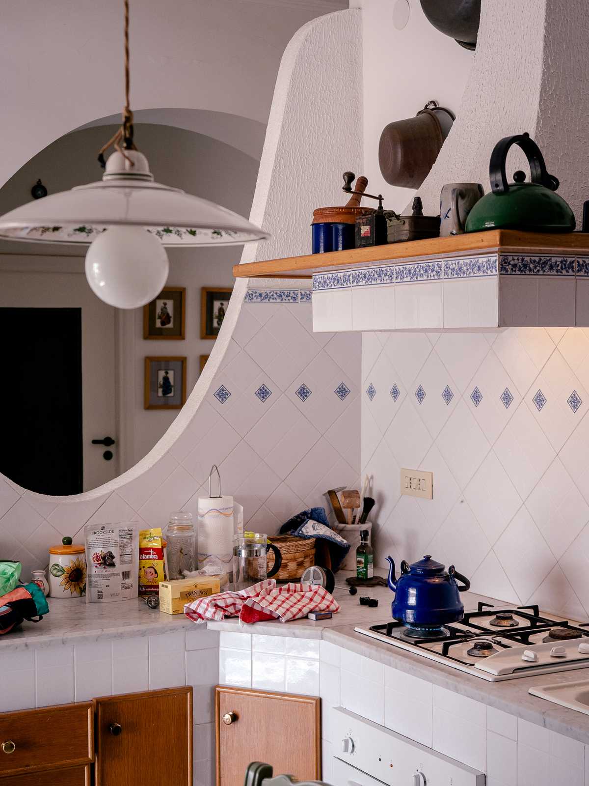 A tile-covered kitchen with a blue teapot on the stove