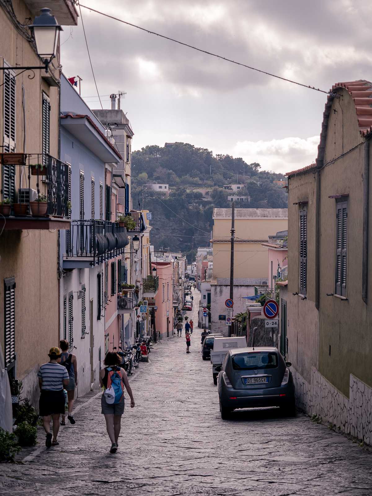 People walk down a cobblestone street on the island of Procida, Italy