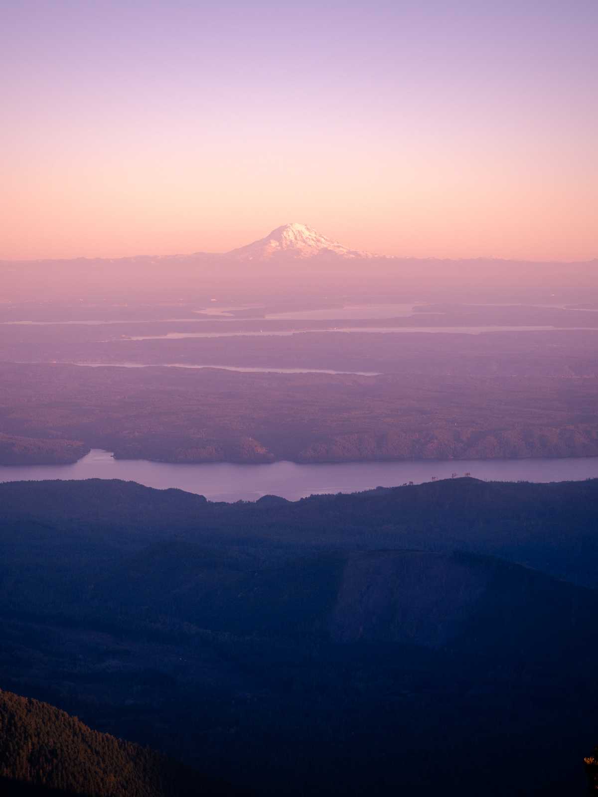 Sunset colors, light sky, looking at Mount Rainier in the distance with ribbons of water crossing the land between