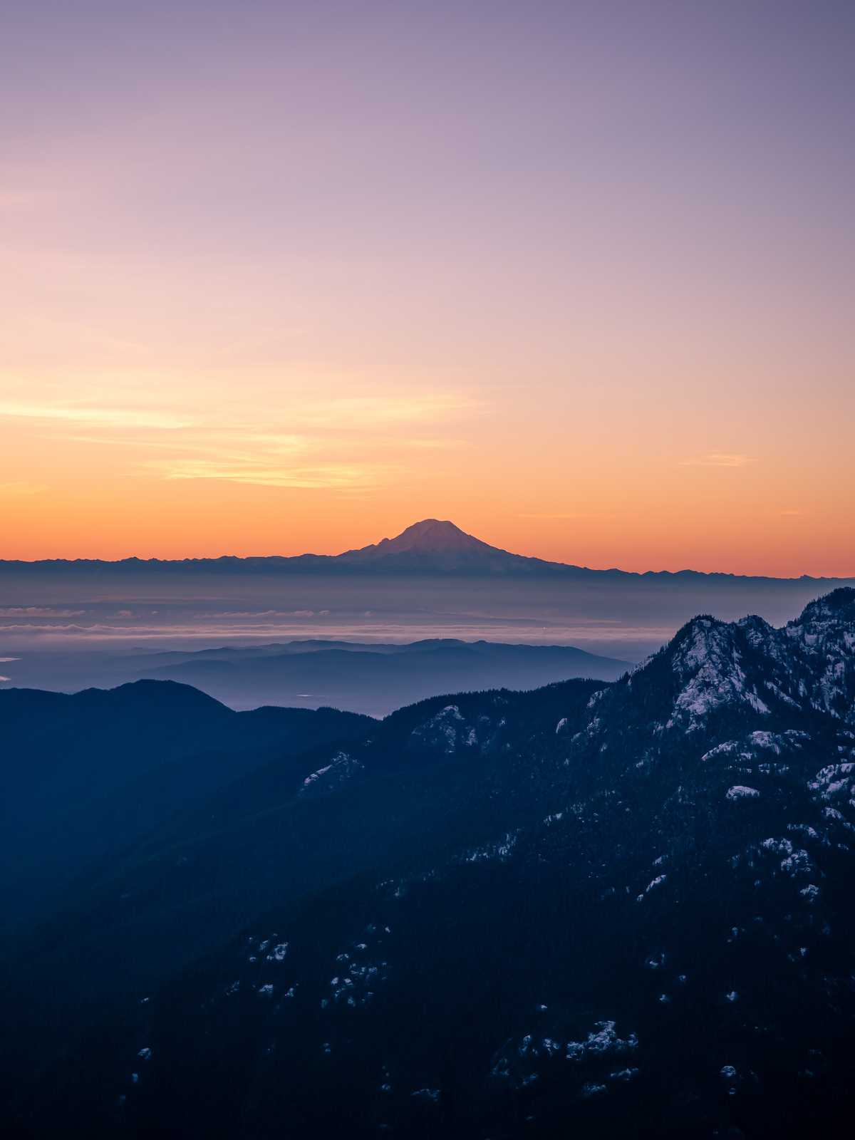 Mount rainier is backlit by the morning sunrise colors