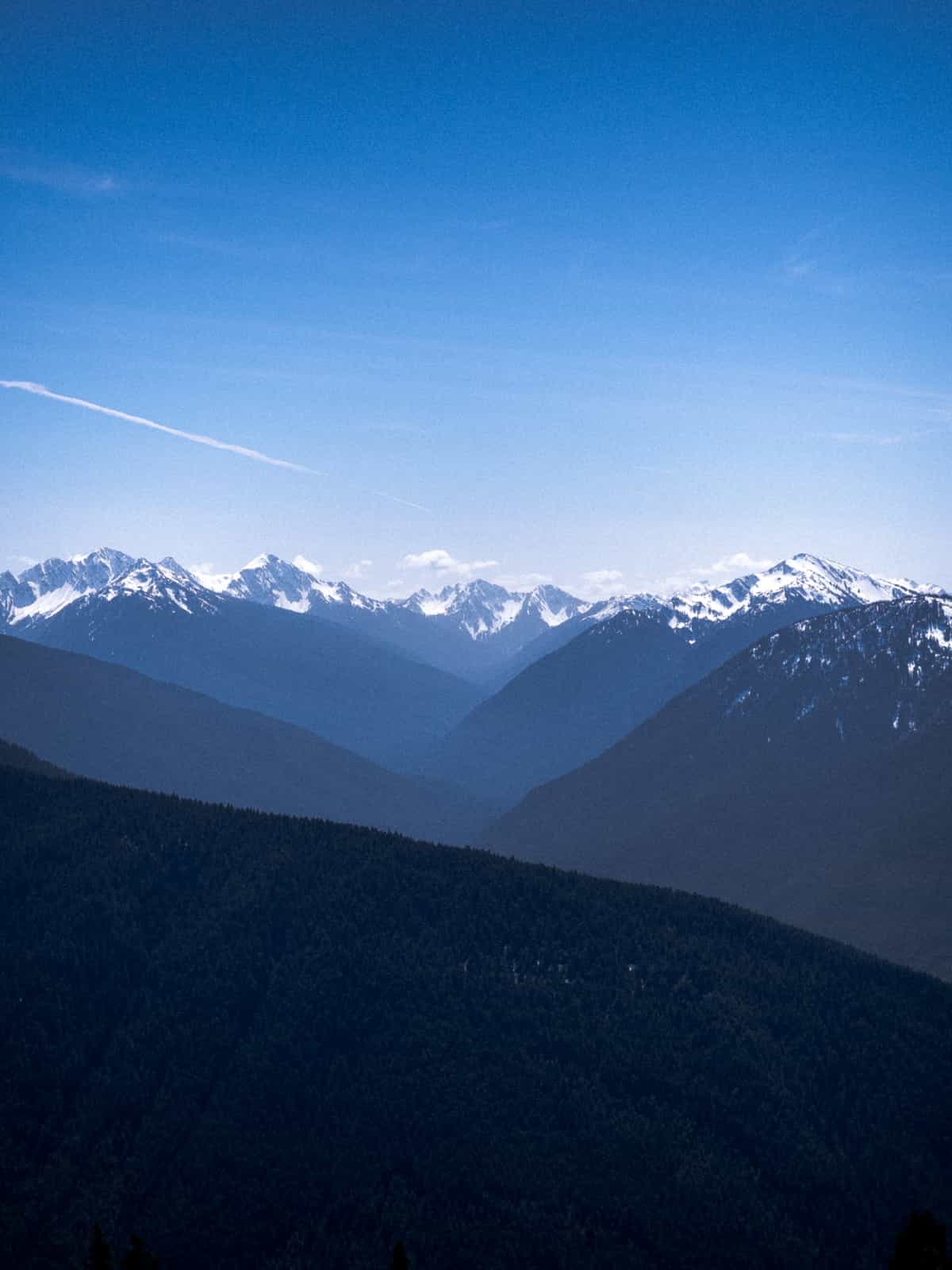 Alternating ridges of mountains, extending into the distance, covered in snow