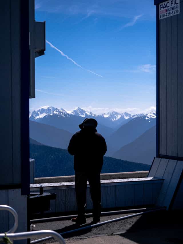 Man stands and looks out at ridges of mountains in the distance