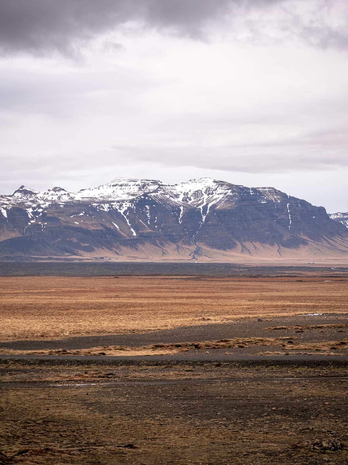 Snow covered mountains rise in the distance, with brown and yellow plains in the foreground.