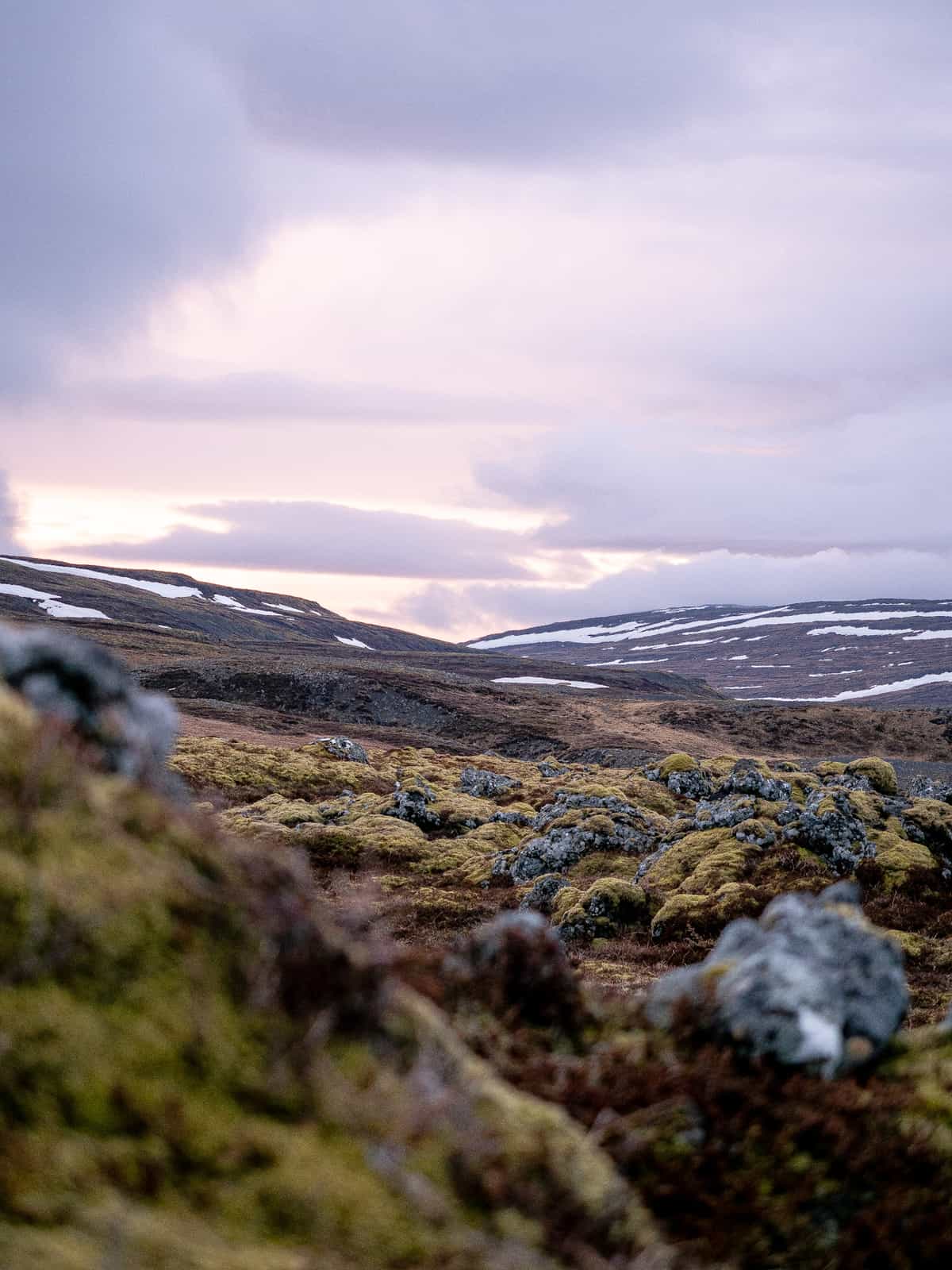 Moss covered stones extend into the distance of a sunset over rolling hills