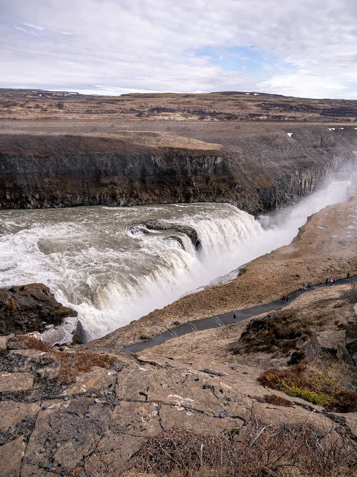 A wide angle view of a very large and wide waterfall into a ravine