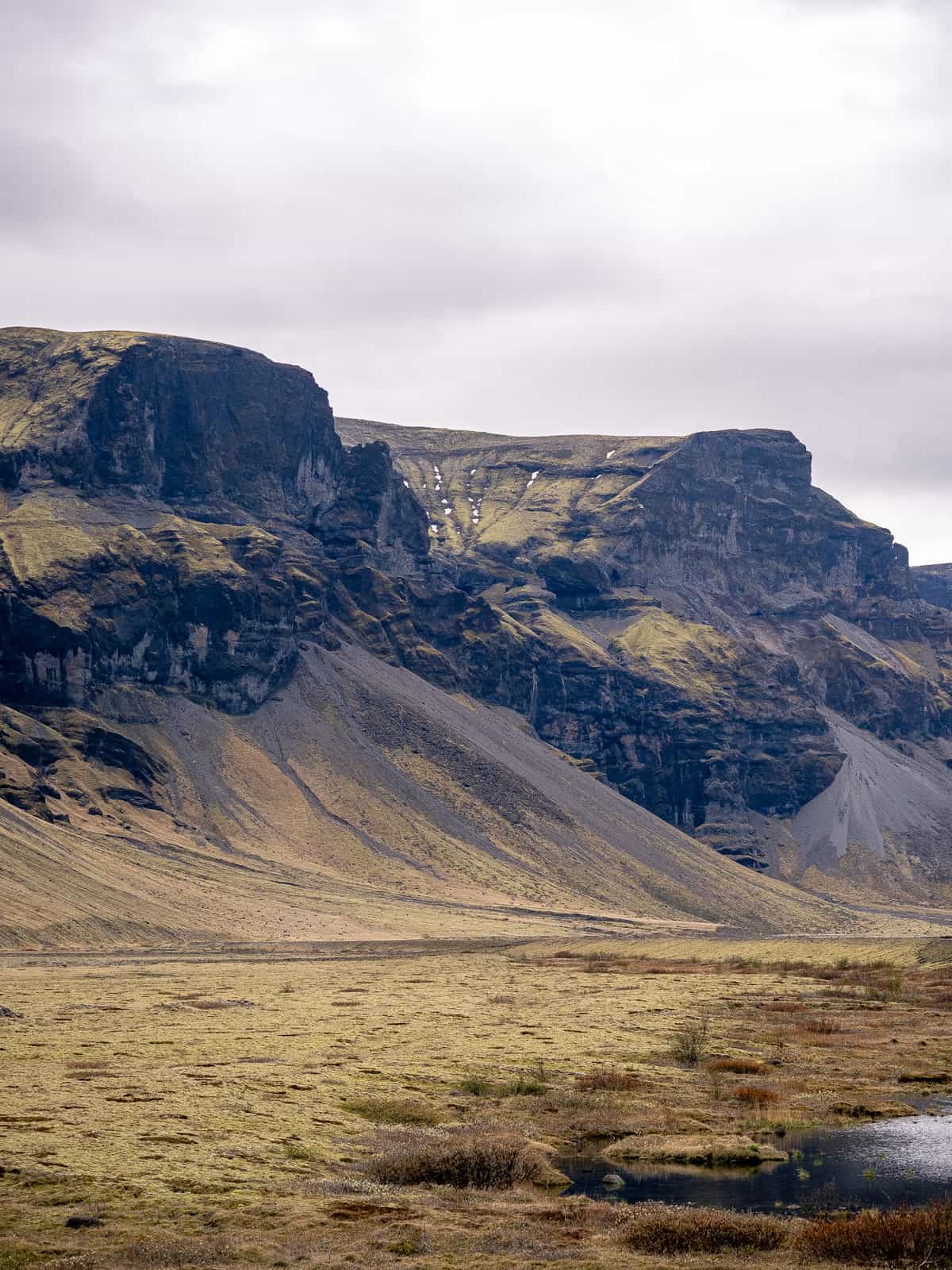 Flat-topped mountains rise from golden plains, with a snowy bowl at the top