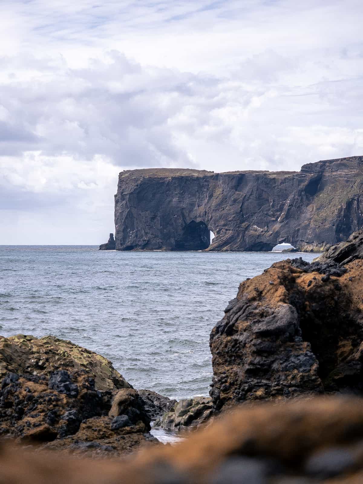 Dark mountain cliffs rise above the ocean