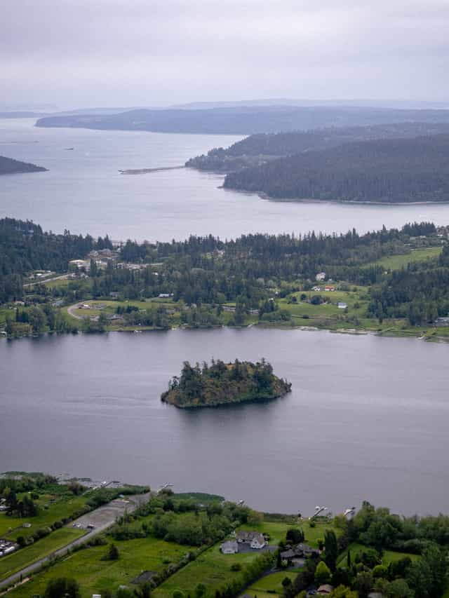 Islands and bands of land with small houses on them are interspersed with water. A lake in the foreground has an island in the middle.