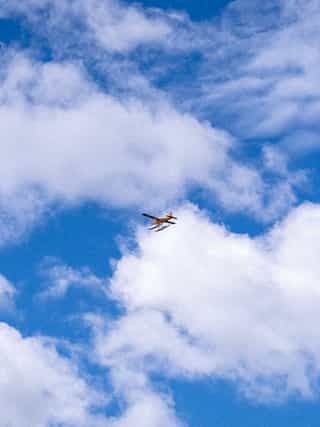 An airplane flies through the sky carrying water buoys